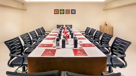 a boardroom seating arrangement with ceiling lights and a corner shelf