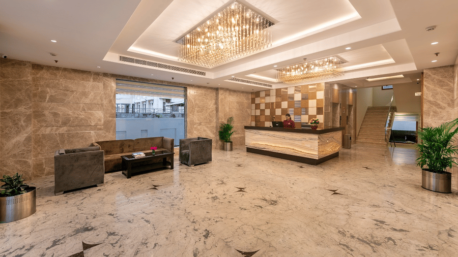 Hotel lobby with marble flooring, chandeliers, and a reception desk.