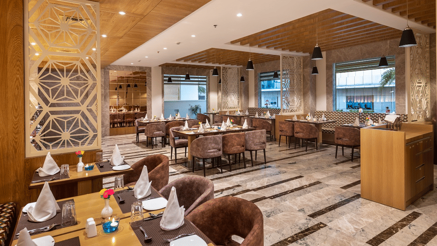 Grand dining area with wooden accents, stylish tables, and neatly arranged setup with water bottles and tissues