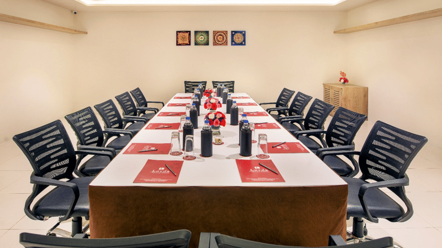 Professional conference room in Lords Inn Jamnagar with organised seating, meeting materials on the table, air conditioning, and refreshments including water bottles and glasses