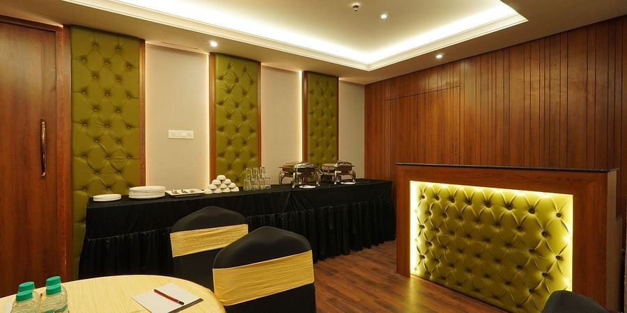 Bright meeting room with a large rectangular wooden table, ergonomic black chairs, floor-to-ceiling windows, and minimalist white walls – Magnus Nexstar Suites, Kalyani Nagar