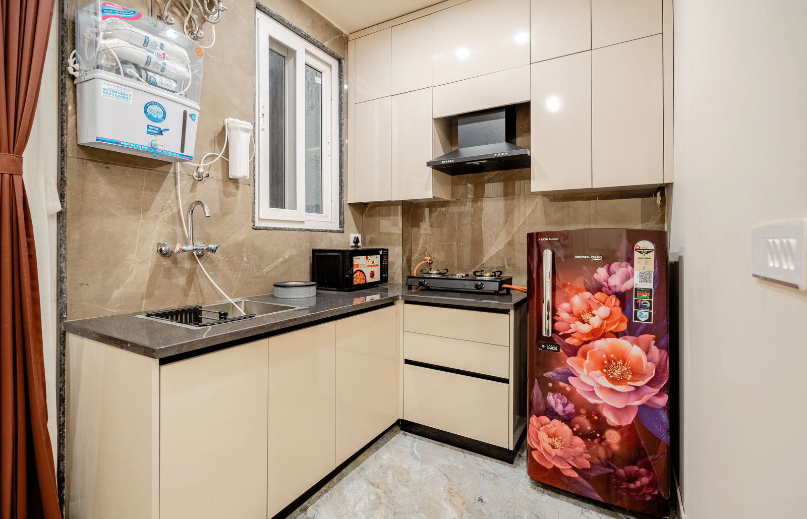 Modern kitchen with cabinets, sink, and refrigerator at Lime Tree 1BHK Service Apartment Near Artemis Hospital Gurgaon.