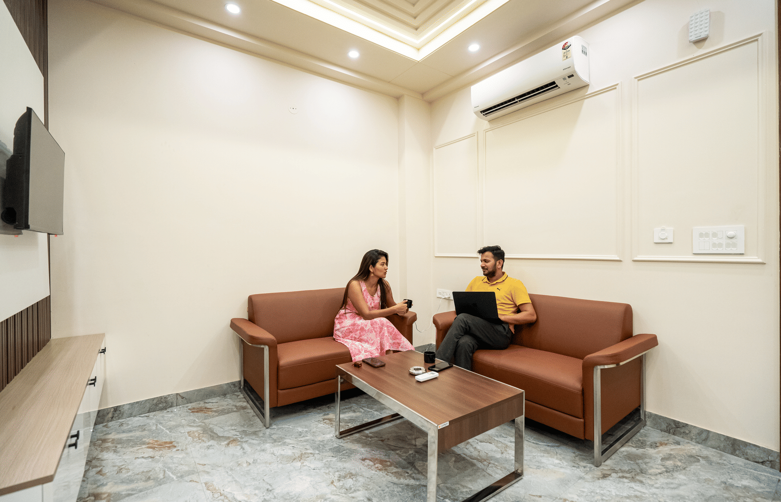 Cosy living room with sofa seating and guests enjoying a relaxed conversation at Lime Tree 1BHK Service Apartment Near Artemis Hospital Gurgaon.