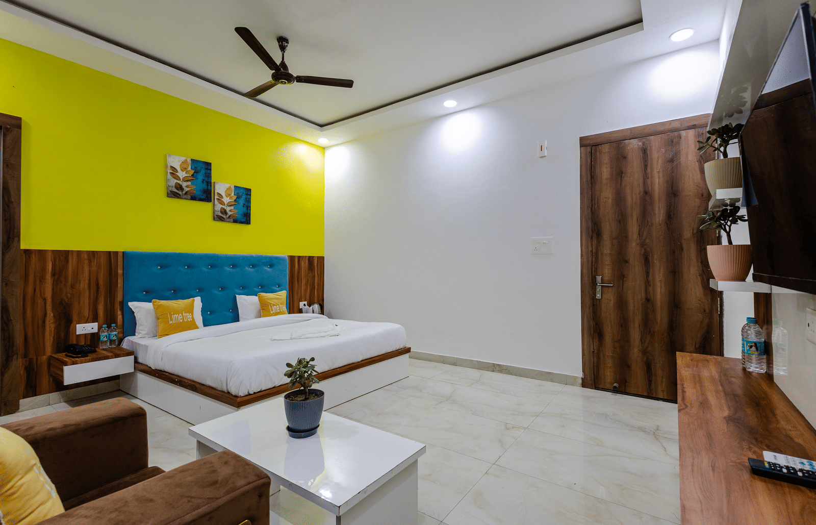 A spacious room with a yellow coloured master wall and a king size bed at Lime Tree Hotels and Banquet, Vrindavan.