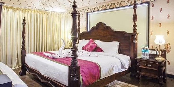 Side view of a room with a bed and a wooden side table beside the bed Rajasthali Resort & Spa Jaipur.