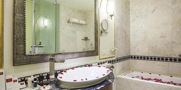 Image of a washroom with a bathtub and a sink decorated with rose petals at Rajasthali Resort & Spa Jaipur.
