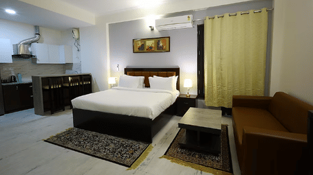 A hotel room with a large bed, kitchenette and seating area, with warm lighting - Lime Tree Golf View, Golf Course Road