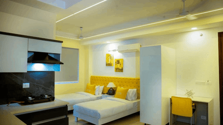 Suite of Lime Tree Hotels & Service Apartment Private Limited featuring a wall mounted television, a work desk, and a bed.