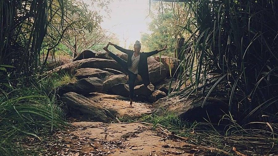 Person silhouetted against light at the end of a bamboo-lined path.
