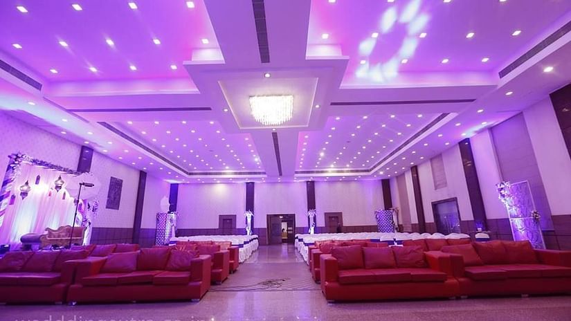 The event hall interior is adorned with red sofas and illuminated by dotted lights on the ceiling - Wedlock Green Dhanbad