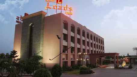 A large hotel building with a red sign on the roof at sunset.
