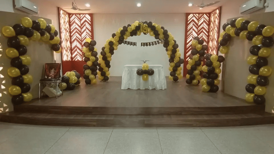 An event space with a decorated stage, balloons, and a white backdrop - Lords Eco Inn Belagavi