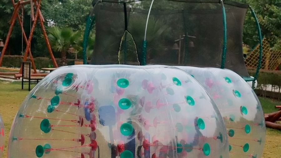 People zorbing in a carpeted lawn at Themis Mudhouse - A Nature's Retreat Resort & Wellness
