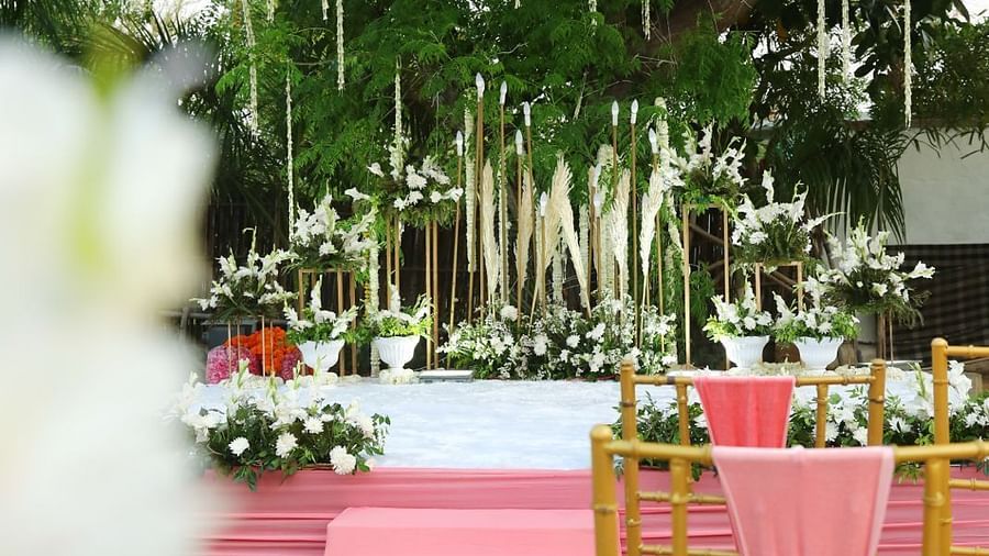 A decorated outdoor space at Tisya Farms, Gurgaon with hanging lights, floral elements, and pink table setups.