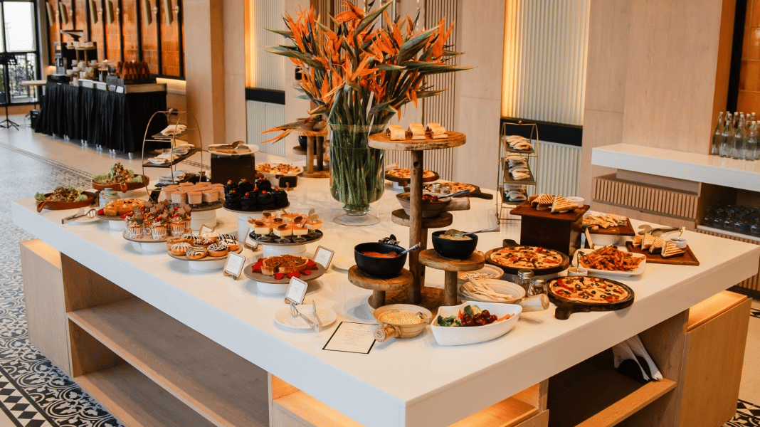 A grand table in the center of the dining space, arranged with different items for a buffet