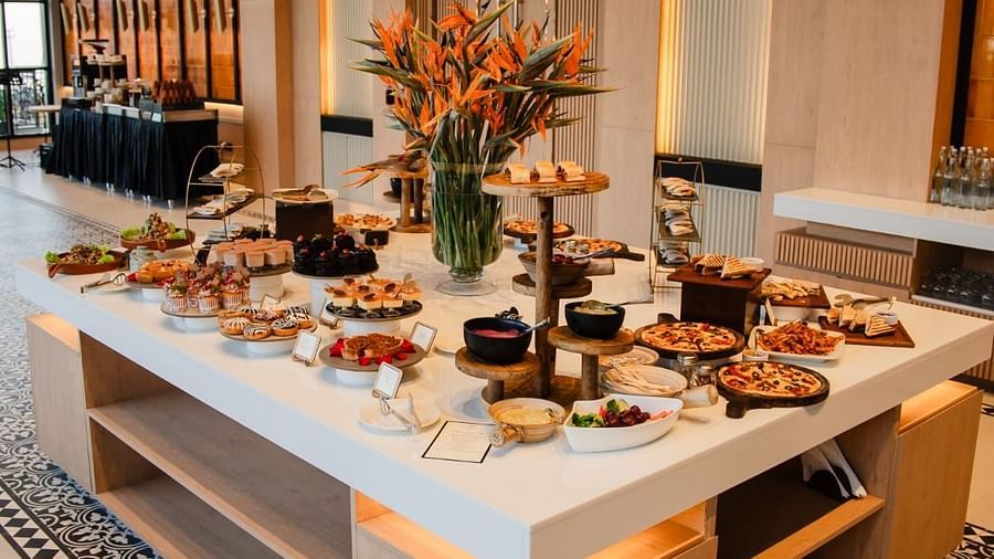 A grand table in the center of the dining space, arranged with different items for a buffet