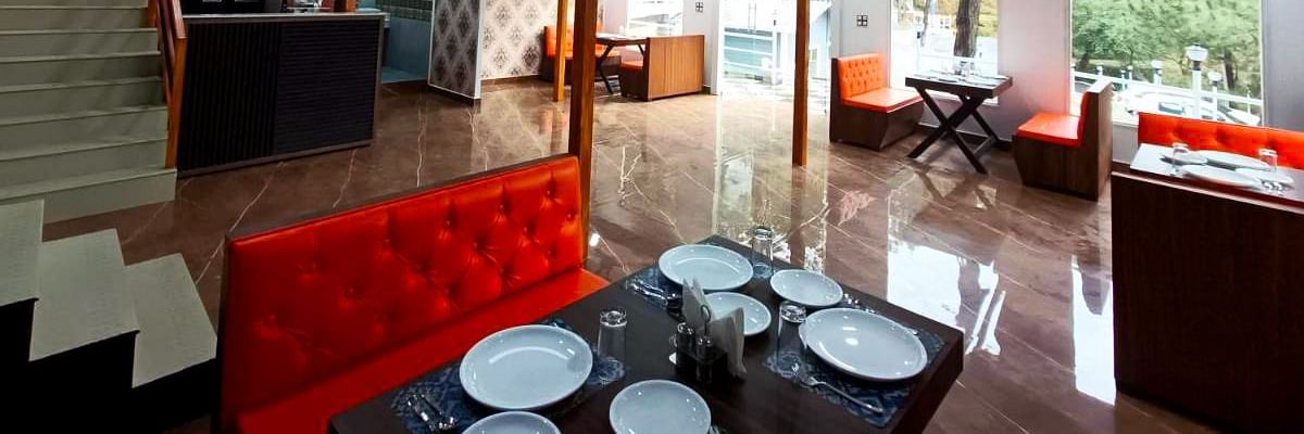 The interiors of the restaurant at DLS Nature Trinket Resort with red couches and tables.