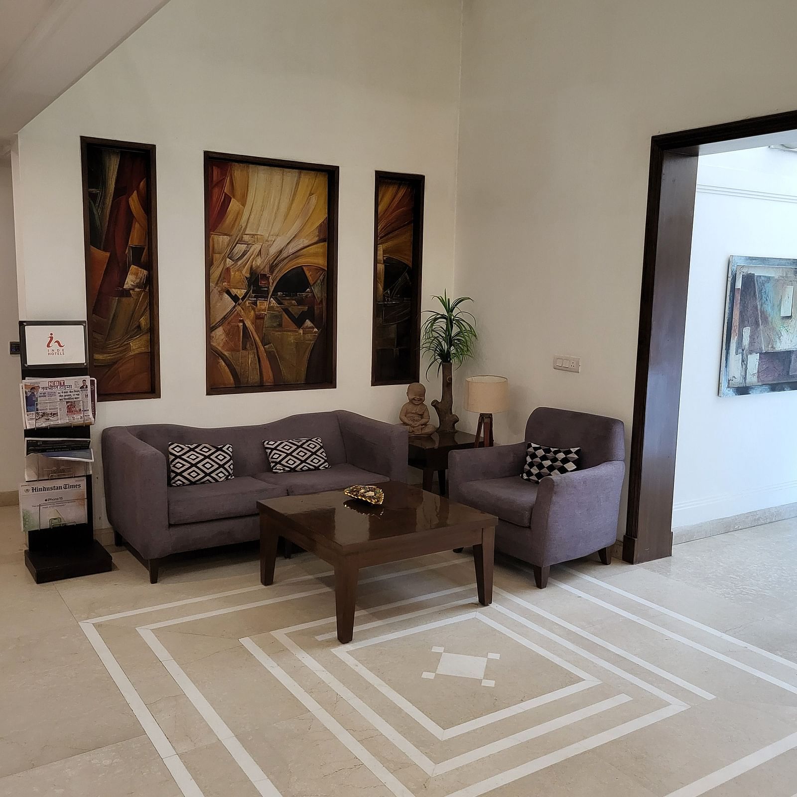 An image of a reception lobby featuring sofa set, centre table, some plants, and photo frames hanged on the wall at Inde Hotel Signature Tower, Gurgaon