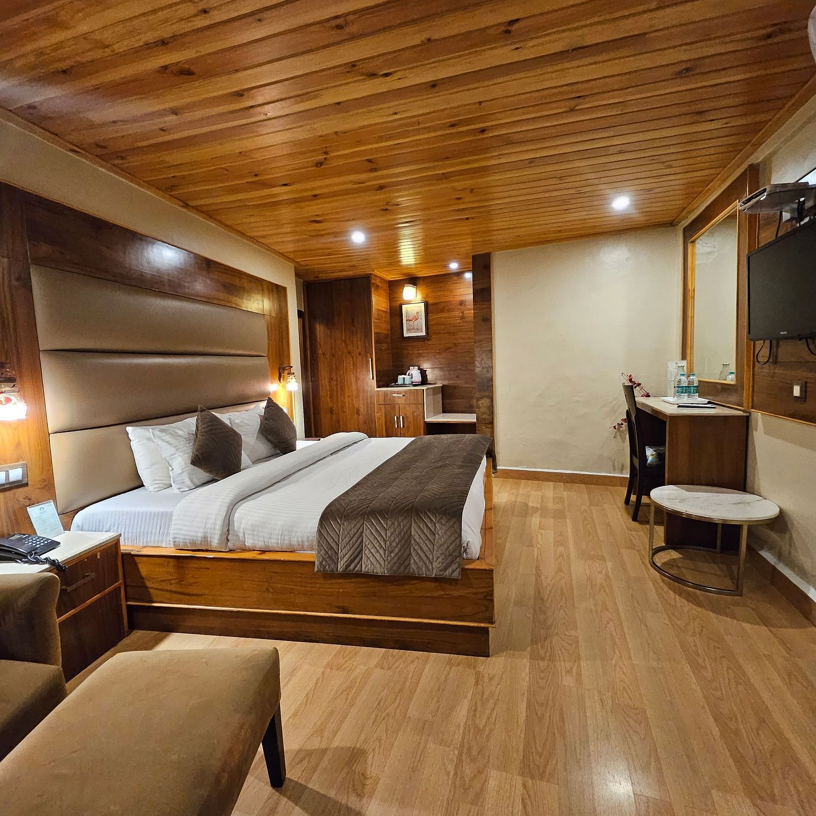 A side view of a well-furnished room with bed, TV, and other amenities | Mongas Hotel & Resort, Dalhousie