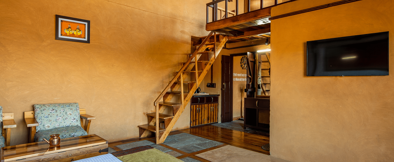 Cosy loft-style bedroom with stone and wooden finishes, featuring a staircase leading to the upper loft area.