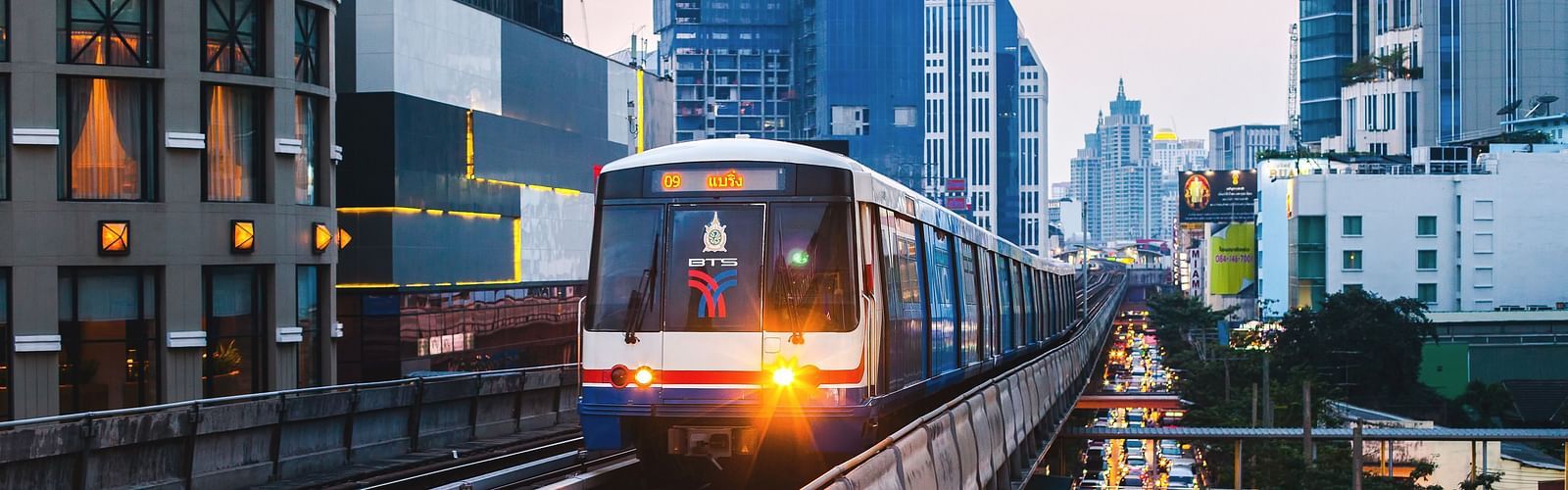 An overview of a train arriving at Asok BTS station with buildings in the background.