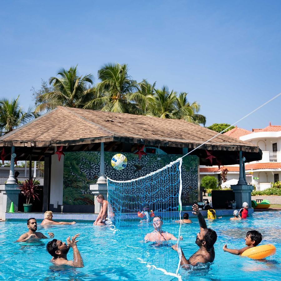 Guests playing water volleyball in the swimming pool at Heritage Village Resorts & Spa, Goa.