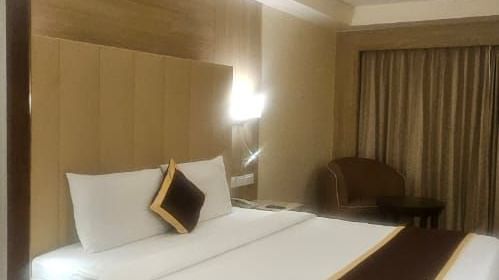 Modern hotel room interior with comfortable bedding and warm lighting at La Classic, Hosur Road.