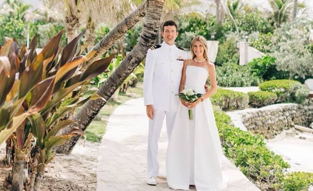 Two people in wedding attire standing among palm trees, Abaco Inn grounds.