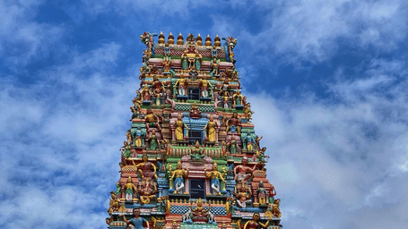 Meenakshi Amman Temple gopuram with vibrant sculptures against a blue sky.