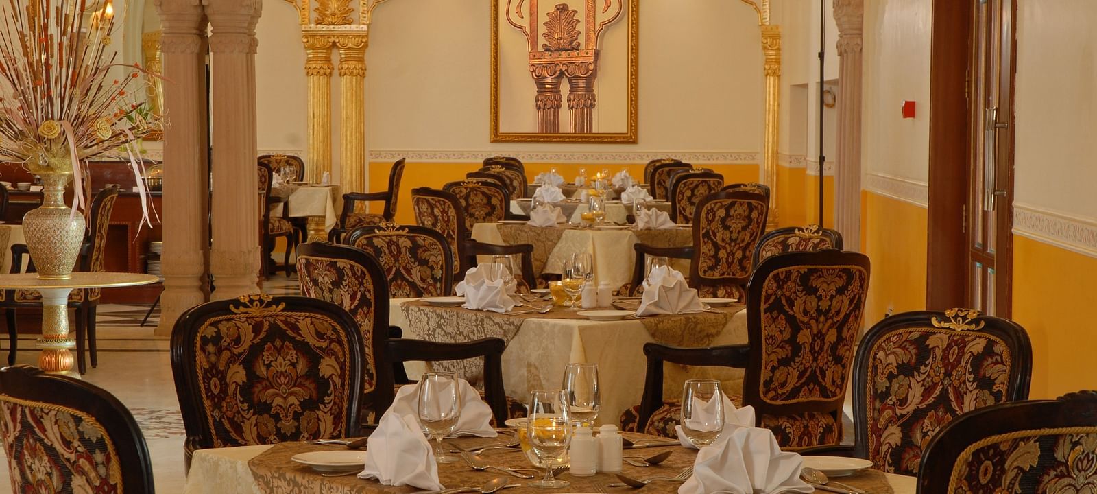 A dining space with seating area a photo frame on the wall at Rajasthali Resort & Spa Jaipur.