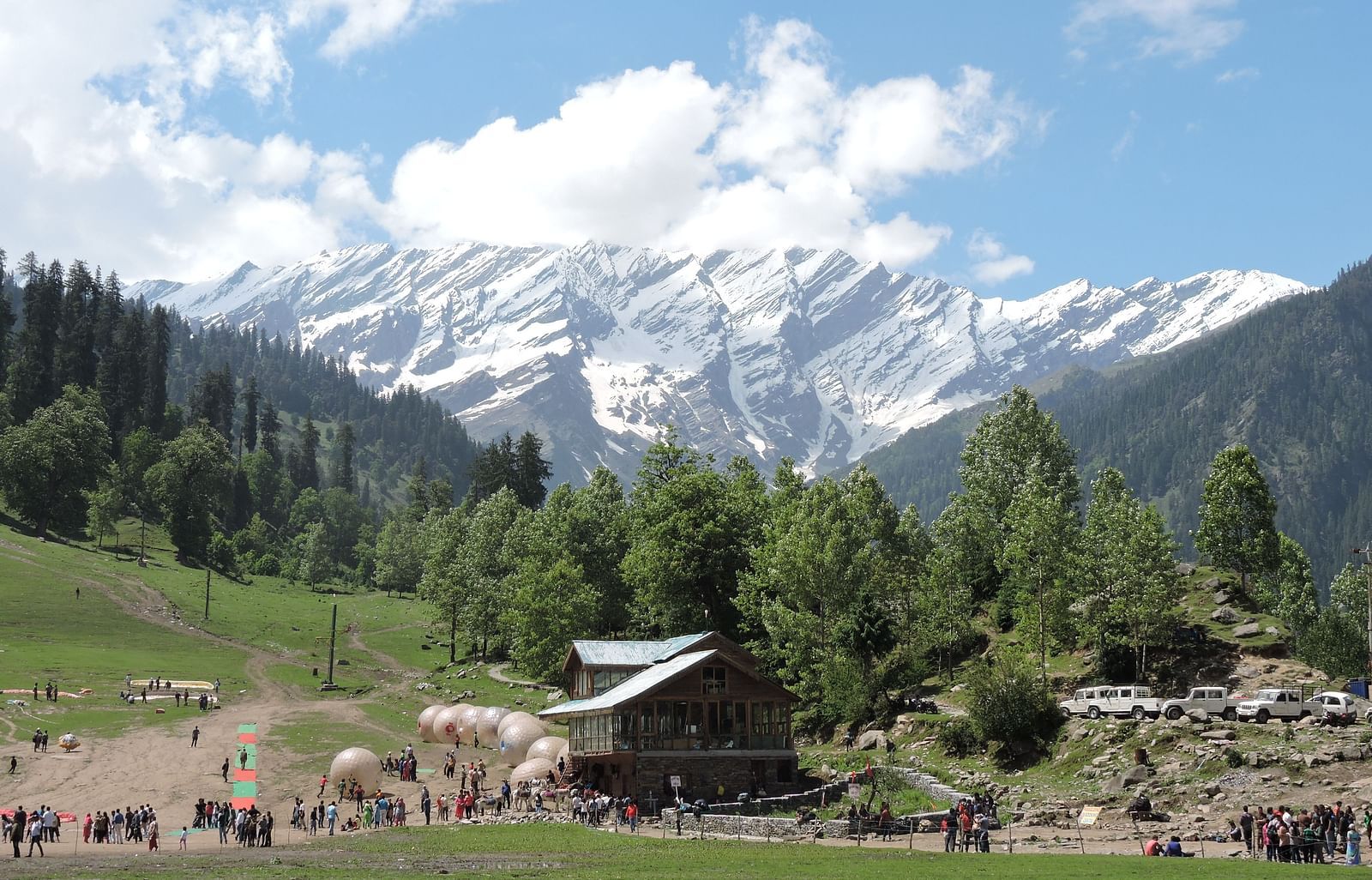 a view of the cottage on a sunny day with snowy mountains in the background