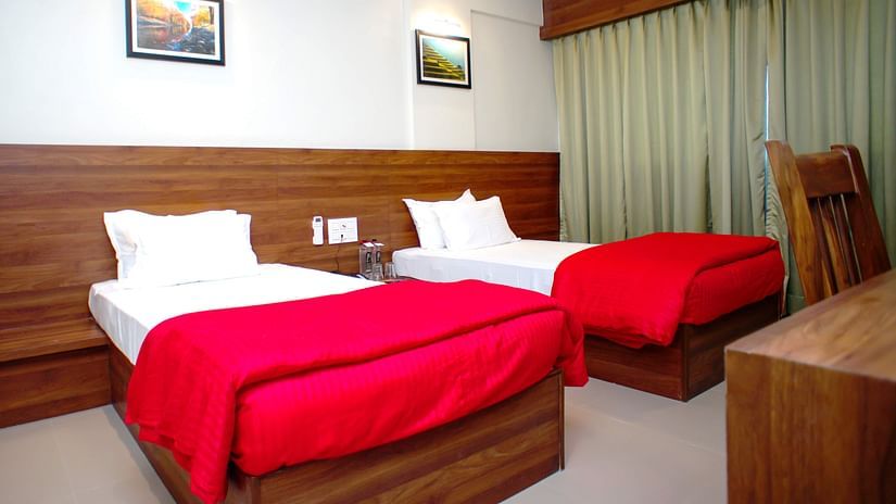 Deluxe With Breakfast room featuring twin beds, a wooden work desk with chair, AC at Mastiff Hotel, Chinchwad, Pune.