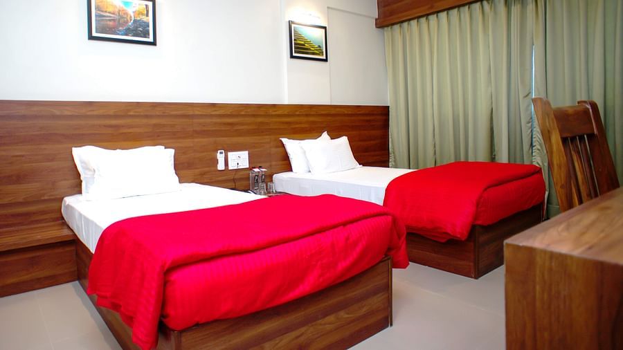 Deluxe With Breakfast room featuring twin beds, a wooden work desk with chair, AC at Mastiff Hotel, Chinchwad, Pune.