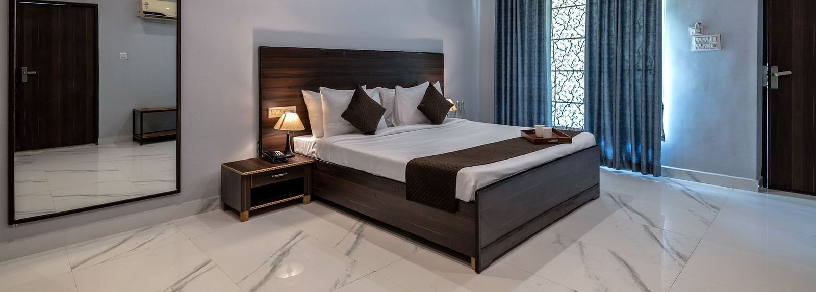 Side view of a room with a bed and a large mirror beside it at Valley by Grassfield.