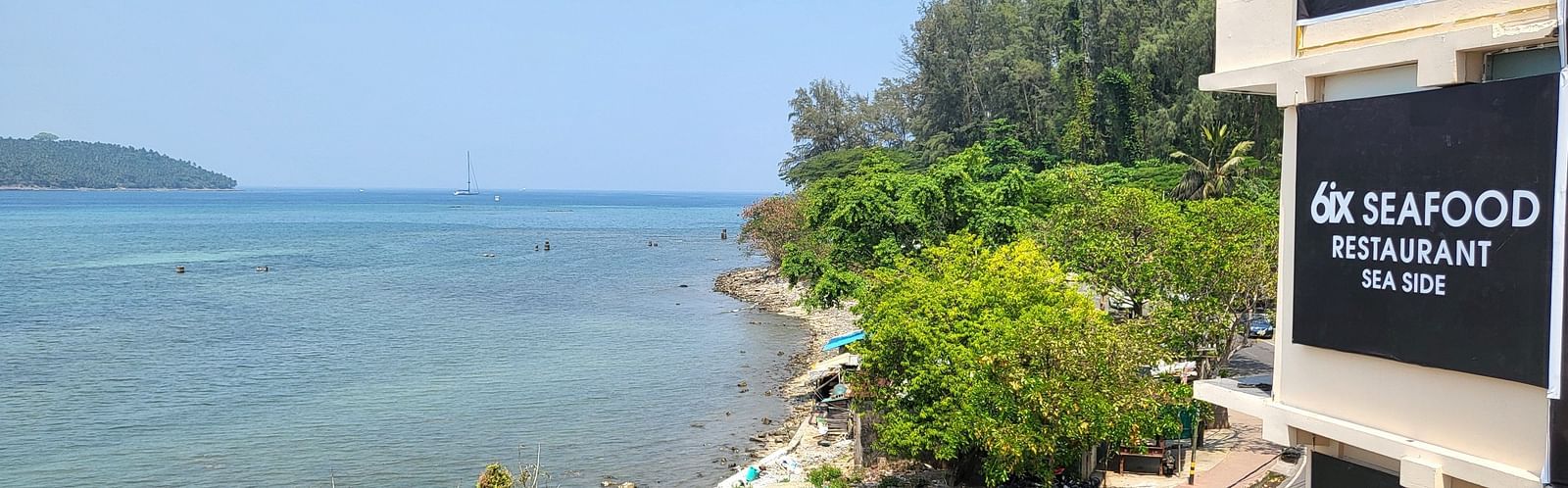 View of the ocean outside 6ix Seashore Hotel, Port Blair along with trees on the shore