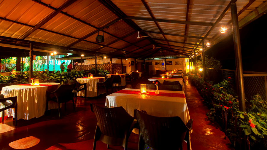 Image of a dining space with lights on the table at Coorg Jungle Camp Backwater Resort, Kushalnagar.