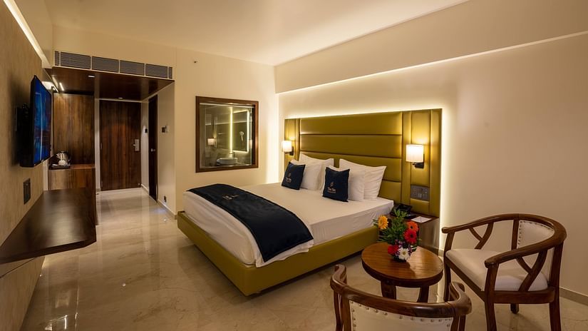 Side view of Deluxe King with plush bed and bedside tables seating area TV set coffee and tea maker and partial view of the washroom - Mastiff Grand - The Sia Palace Suites Banquets Khopoli