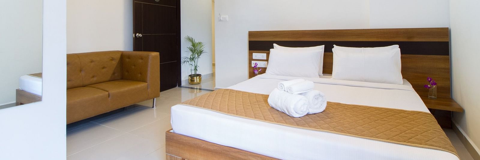 A hotel room including a double bed with bedding and an armchair at Sanctum Suites Whitefield, Bangalore.