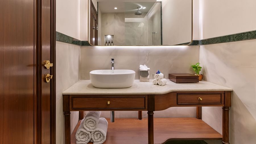 The Premium King Garden View Room at The Ummed Ahmedabad features an elegant ensuite bathroom with a well-lit sink, mirror, and spacious counter