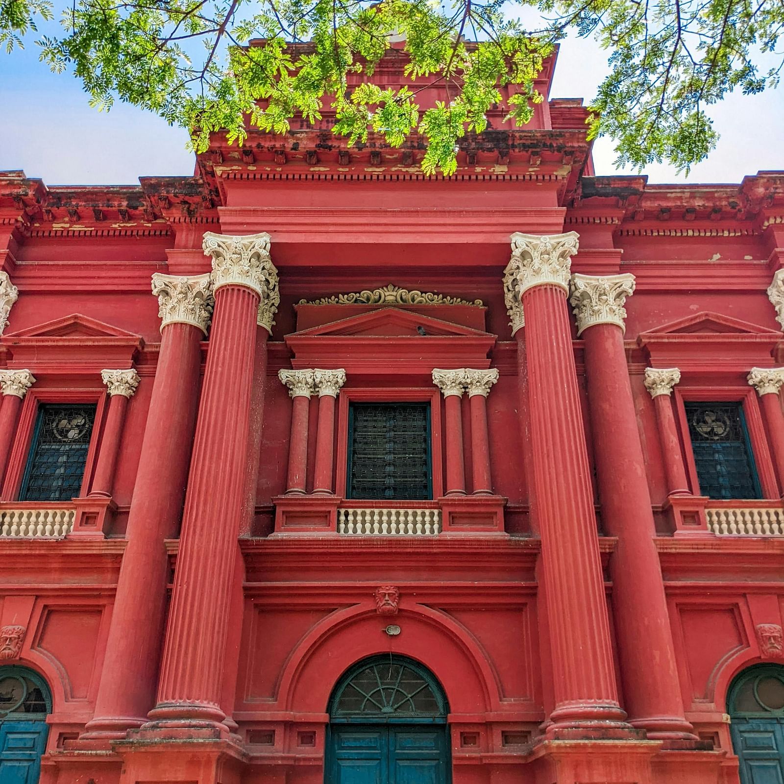 facade view of a bright red building with teal coloured wooden doors
