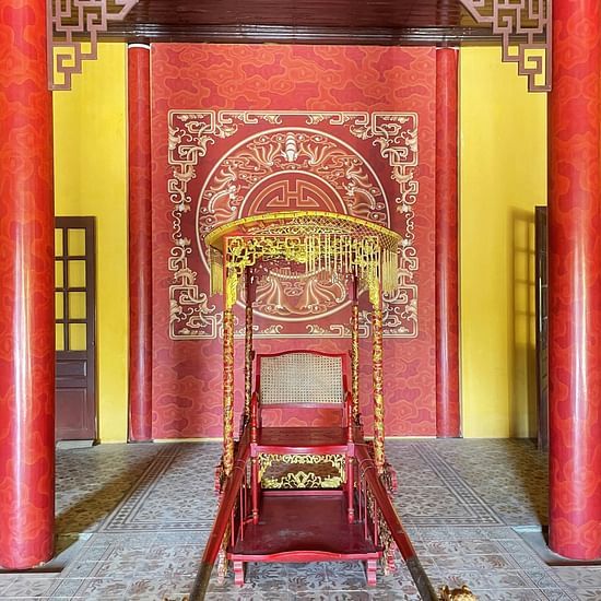 An overview of a palanquin in front of a temple with red door and an arch above the palanquin