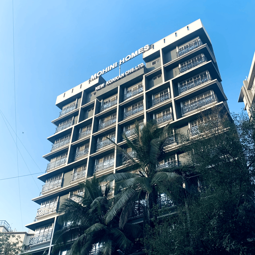 Low-angle view of the multi-storey Home2 Residency, Mumbai Airport, building facade against a bright blue sky.