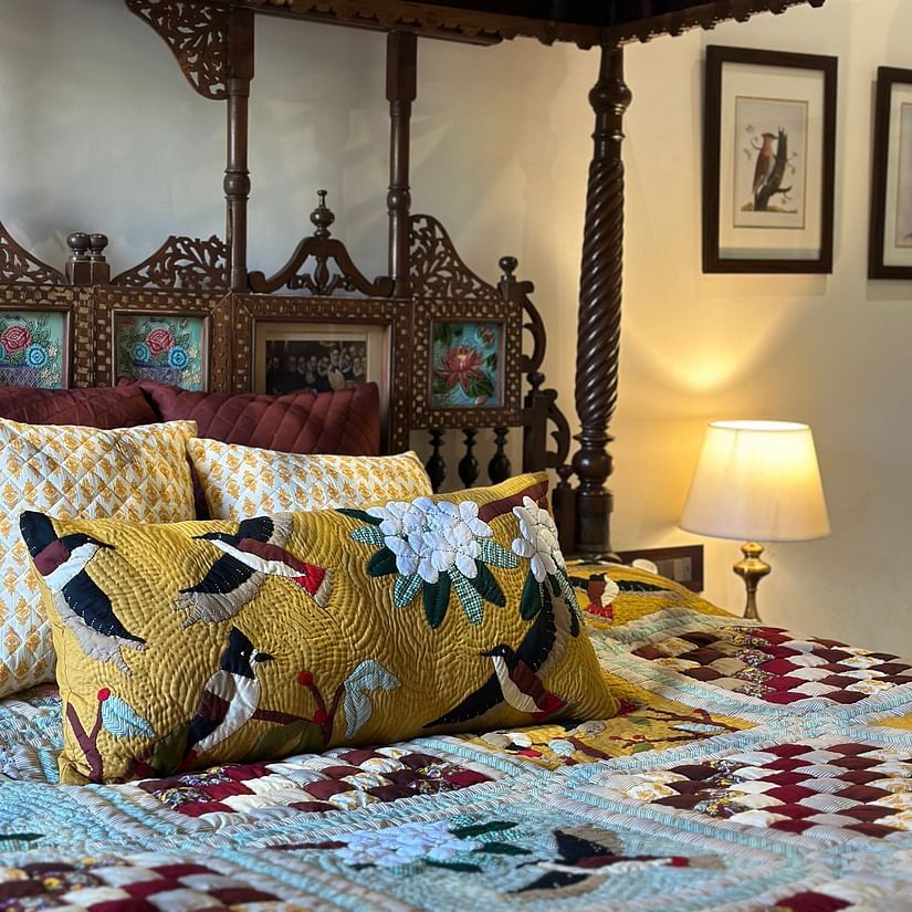 Image of a hotel room with a bed, pillows and paintaings