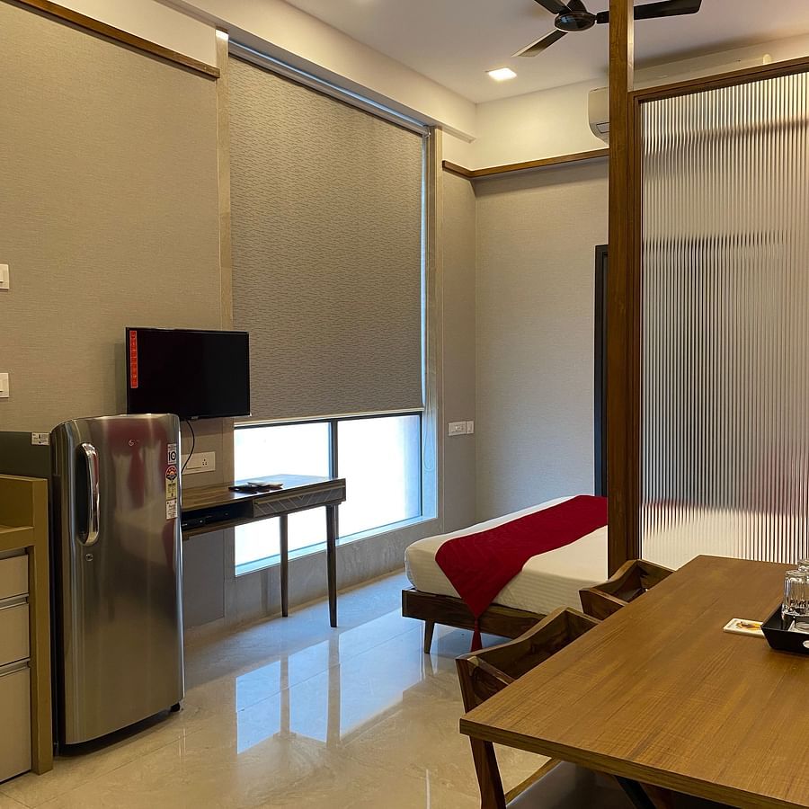 private studio apartment with television, work desk and chair, and refrigerator