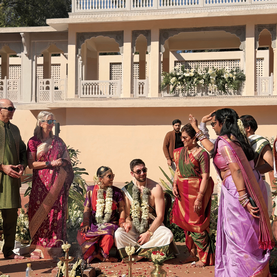 A group of family members and guests gathered in a sunny courtyard for a traditional Indian wedding ritual setup at Umaid Palace.