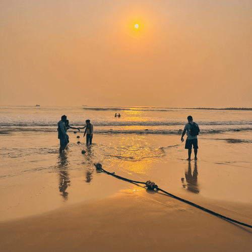 Silhouettes of people standing on a beach during a vibrant sunset.