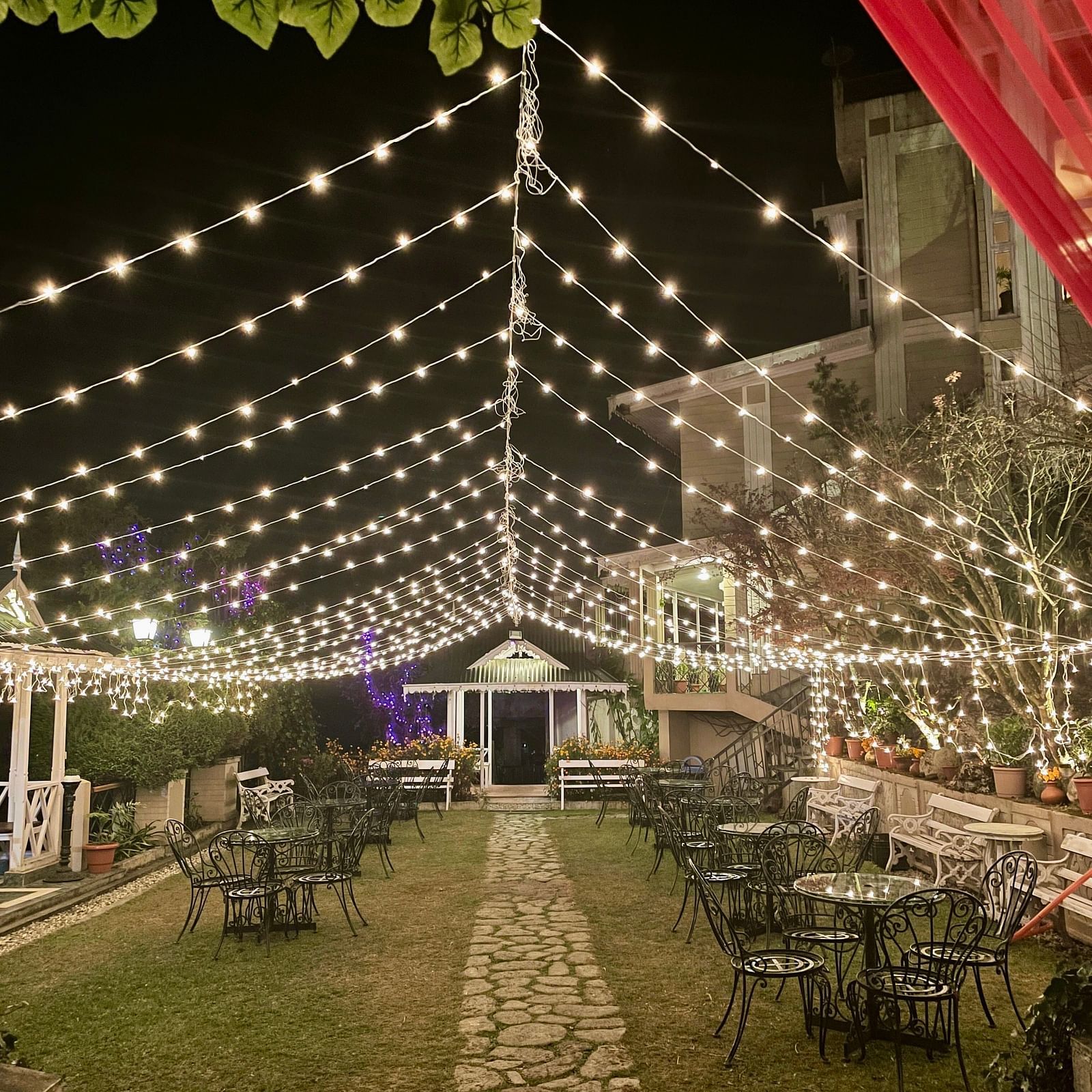 Evening wedding event at Cedar Inn, Darjeeling, showing festoon lights over the garden walkway and decorated seating area.