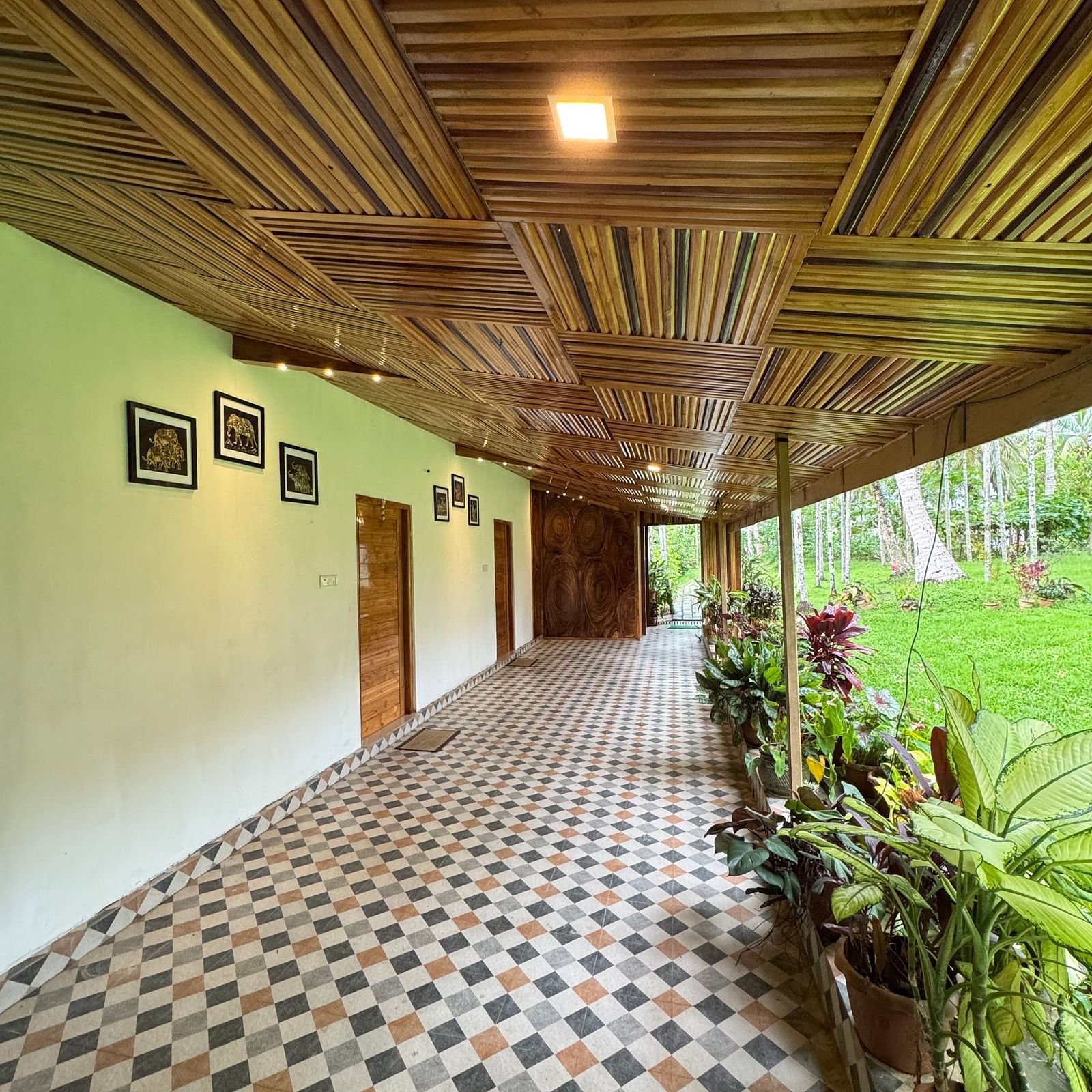A view down a spacious corridor or verandah featuring a geometric tiled floor and a richly textured wooden ceiling.