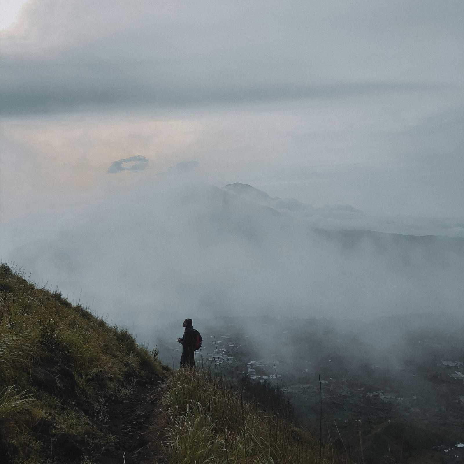 Image of a person standing on a hilltop with mist in the background.
