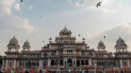 Exterior of a palace during a cloudy day with birds flying over it